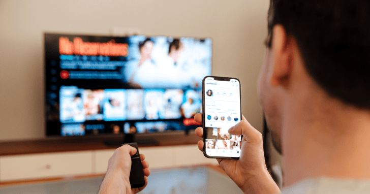 スマートフォンを確認しながら動画配信サービスを見ている男性のイメージ